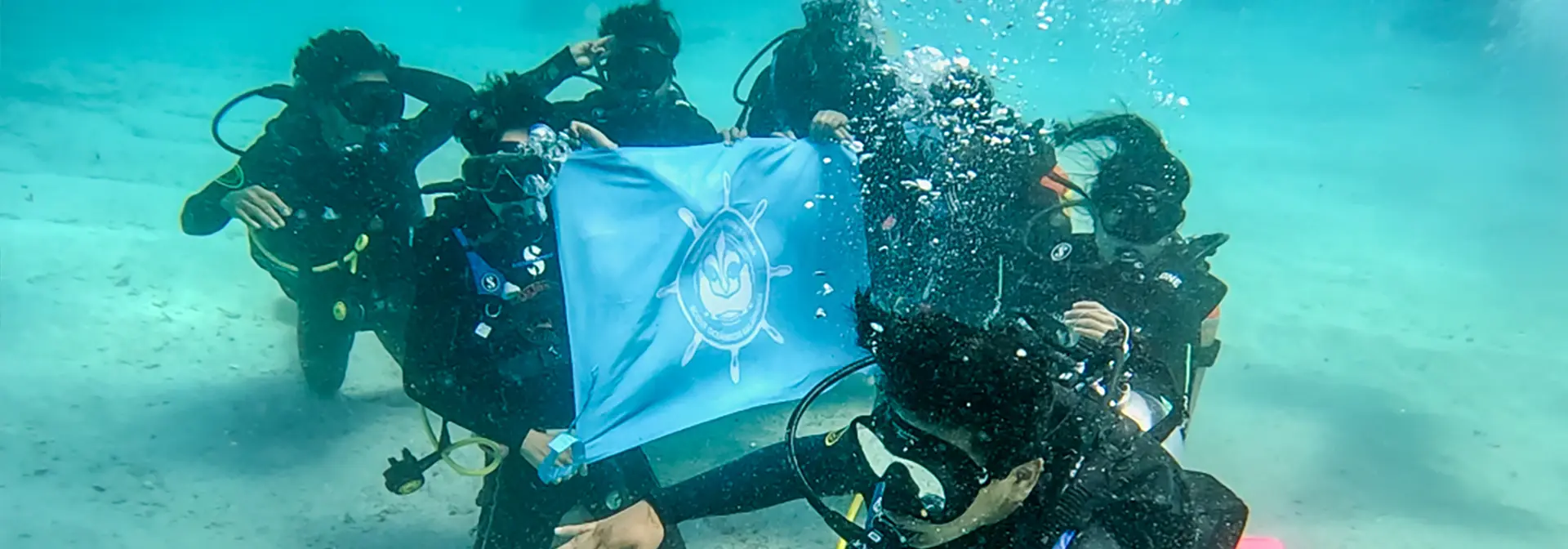 Scouts with their flag underwater in the Galapagos Ocean